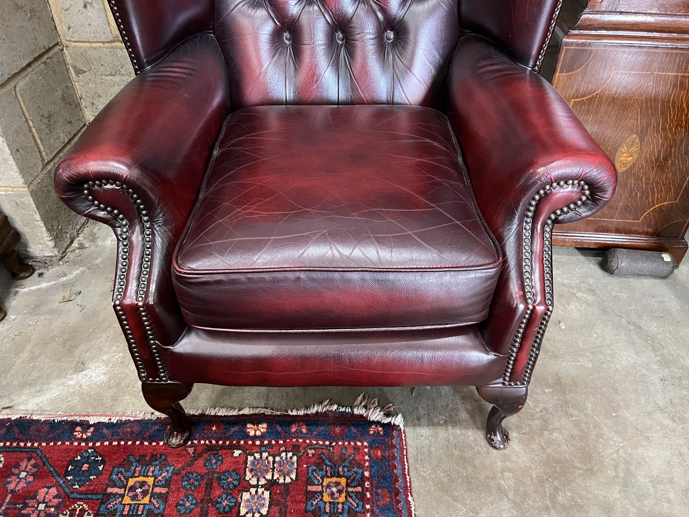 A pair of Victorian style buttoned burgundy leather high back wing armchairs, width 80cm, depth 86cm, height 152cm